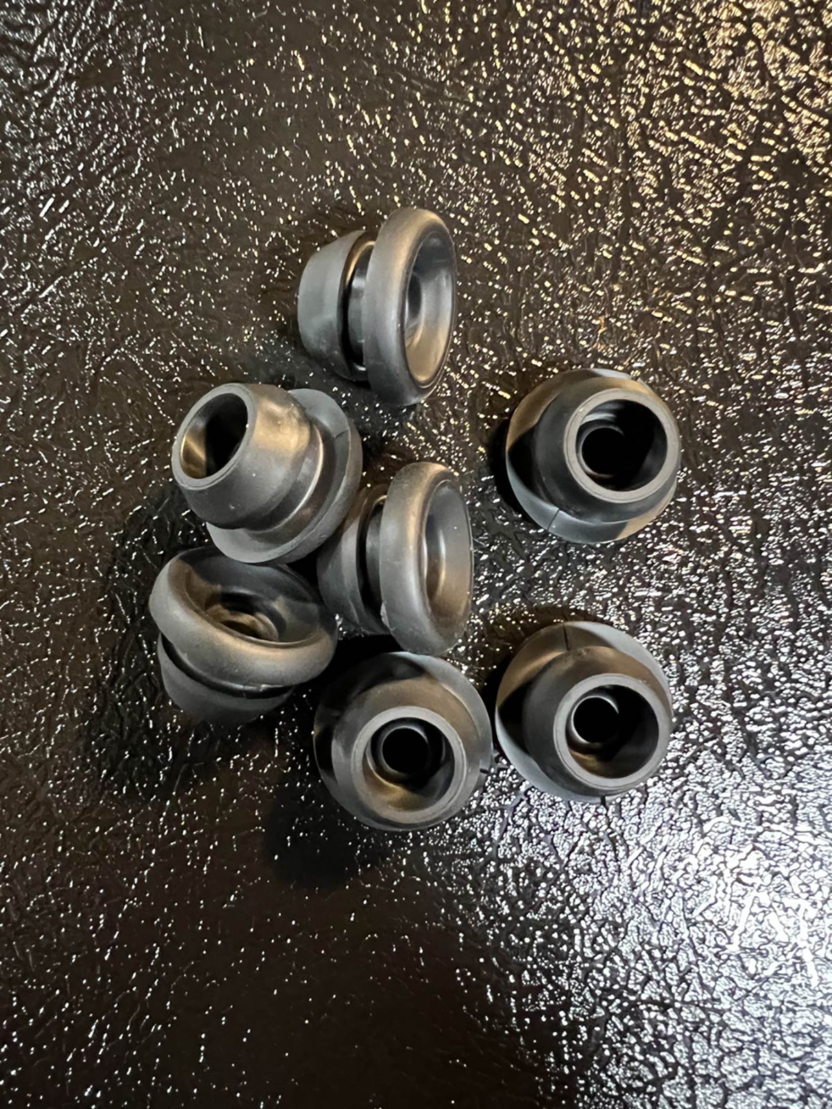 collection of small black rubber automotive grommet parts